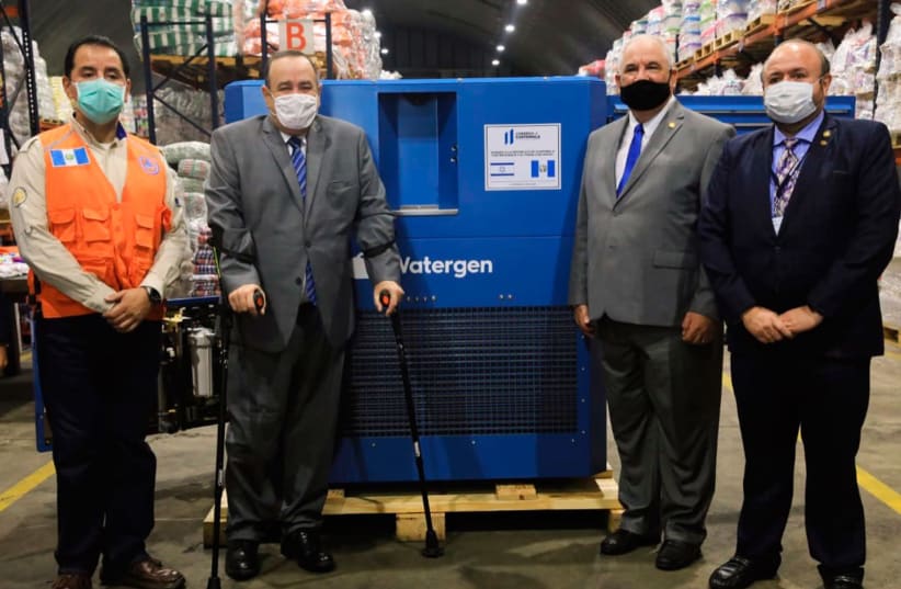 Representatives from Israel and Guatemala stand near a GEN-M atmospheric water generator.  (photo credit: WATERGEN)