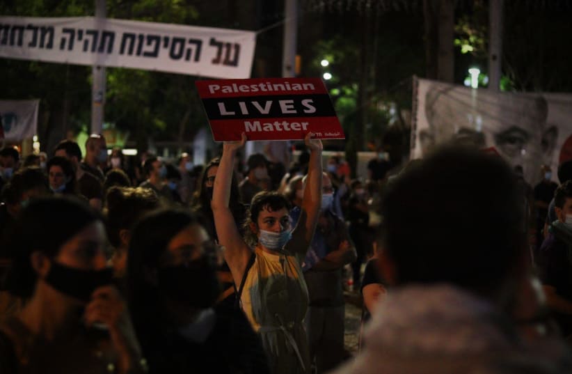 A protester carrying a "Palestinian Lives Matter" sign at a Tel Aviv protest (photo credit: LEON SVERDLOV)