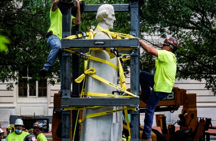 A caged statue of Confederate President Jefferson Davis is strapped to a truck after being removed from the state capital in Frankfort, Kentucky, U.S. June 13, 2020. (photo credit: BRYAN WOOLSTON/REUTERS)