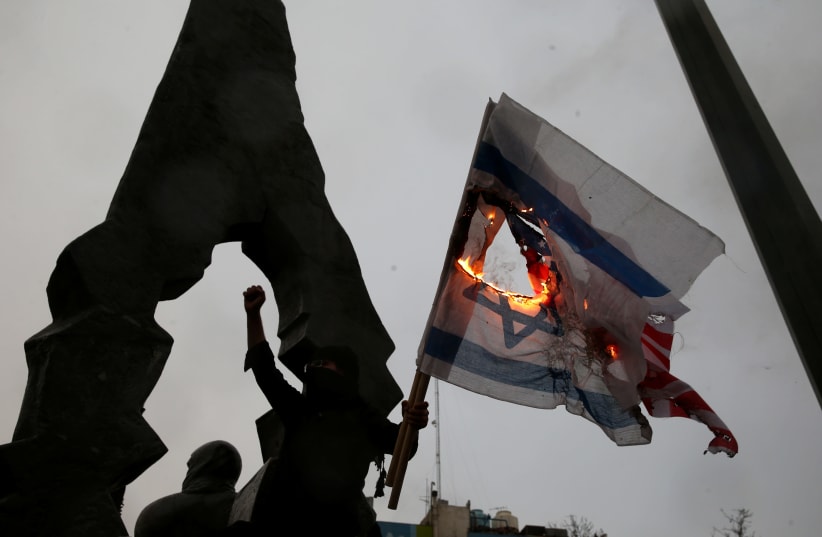 Iranians burn U.S and Israeli flags as they gather to mourn General Qassem Soleimani, head of the elite Quds Force, who was killed in an air strike at Baghdad airport, in Tehran, Iran January 4, 2020 (photo credit: NAZANIN TABATABAEE/WANA VIA REUTERS)