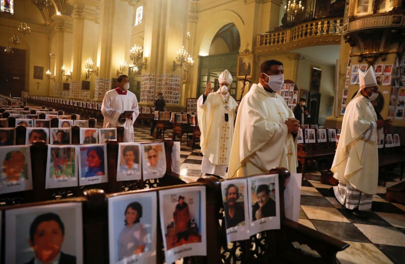 Archbishop Carlos Castillo blesses thousands of photographs, attached on pews and the walls of the Cathedral of Lima, of Peru's victims of the coronavirus disease (COVID-19), in Lima, Peru June 14, 2020 (photo credit: REUTERS)