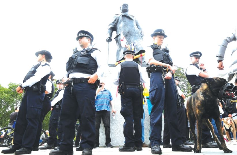 POLICE OFFICERS surround the statue of Winston Churchill in London’s Parliament Square on June 9. (photo credit: TOBY MELVILLE/REUTERS)