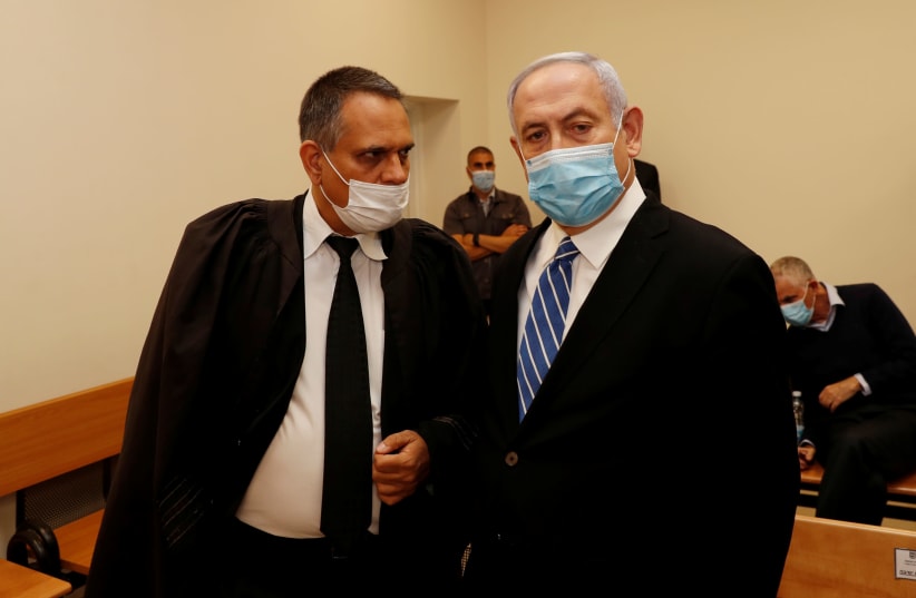 Prime Minister Benjamin Netanyahu, wearing a mask, stands inside the courtroom as his corruption trial opens at the Jerusalem District Court May 24, 2020. (photo credit: REUTERS/RONEN ZEVULUN)