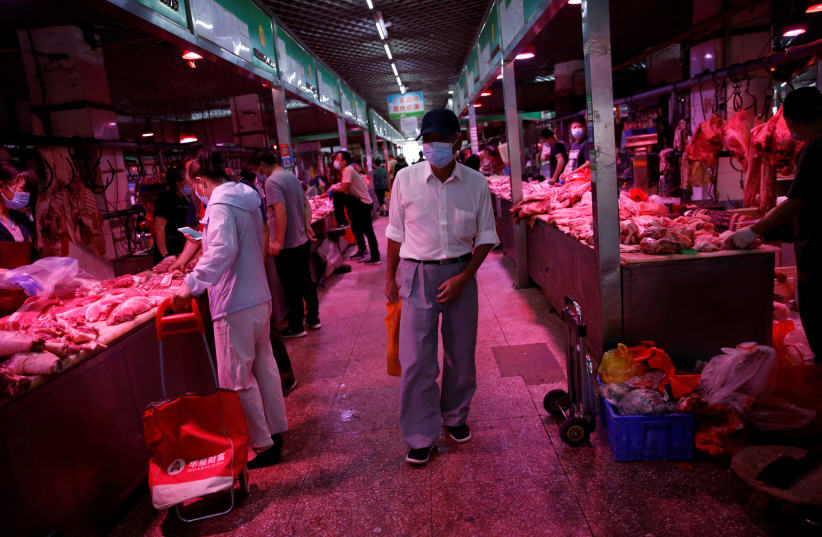A customer wearing a face mask shops at pork meat hall inside the Yuegezhuang wholesale market, following new cases of coronavirus disease (COVID-19) infections in Beijing, China June 17, 2020 (photo credit: REUTERS/TINGSHU WANG)