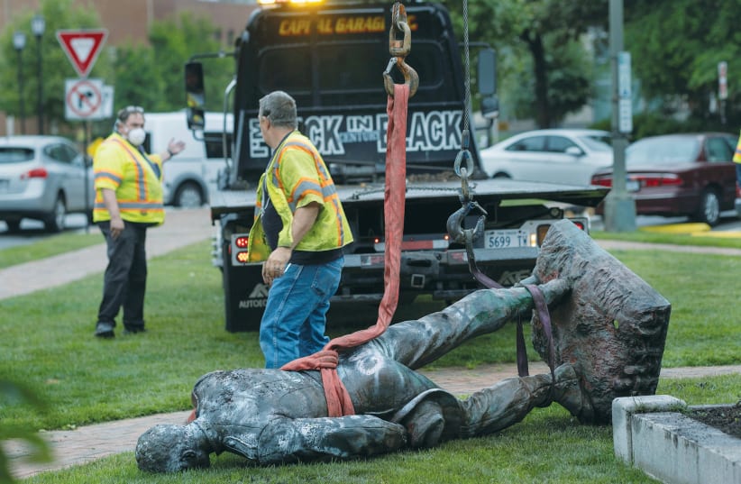 WORKMEN GET READY to load the toppled Richmond Howitzers Monument, erected in 1892 to commemorate a Confederate artillery unit, onto a truck, after protesters against racial inequality pulled it down in Richmond, Virginia, on Wednesday. (photo credit: JAY PAUL/REUTERS)