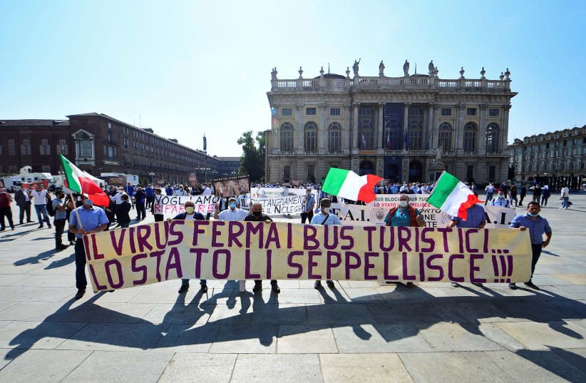 Owners and drivers of tourist buses hold a banner reading "The virus stops tourist buses... the state buries them!!!" Turin, Italy June 3, 2020 (photo credit: MASSIMO PINCA/REUTERS)