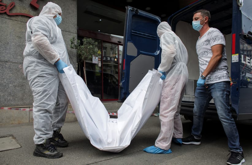 Forensic medicine staff carry a body bag, allegedly containing the remains of Gholamreza Mansouri, outside a hotel in downtown Bucharest, Romania, June 19, 2020. (photo credit: REUTERS)