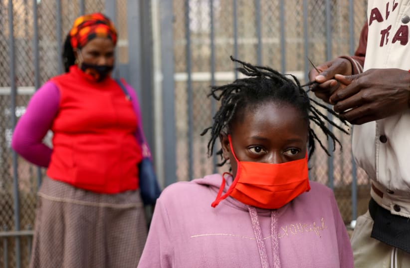 A young woman has her hair done by a roadside hairdresser in Johannesburg on June 6 (photo credit: REUTERS/ SIPHIWE SIBEKO)