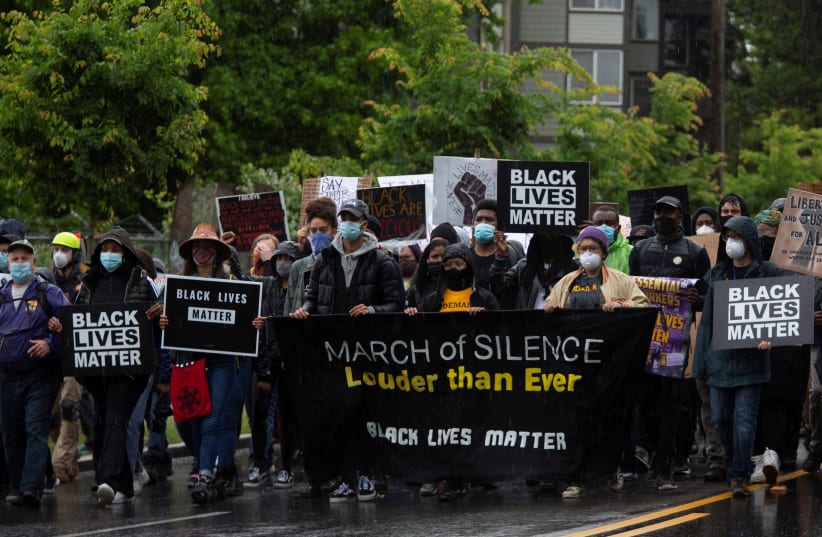 Protesters walk in the rain down 23rd Avenue South in Seattle on June 12 during a silent march organized by Black Lives Matter to protest against racial inequality in the aftermath of the death of George Floyd  (photo credit: REUTERS/LINDSEY WASSON)