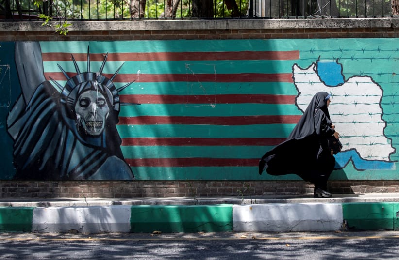 A woman walks past the mural showing U.S. flag with barbed wire and the Statue Of Liberty with skull face in Tehran, Iran June 25, 2019. (photo credit: REUTERS)