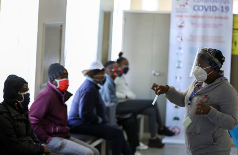 A medical worker talks to volunteers as they wait to receive an injection during the country's first human clinical trial for a potential vaccine against the novel coronavirus, at the Baragwanath hospital in Soweto, South Africa, June 24, 2020.  (photo credit: REUTERS/SIPHIWE SIBEKO)