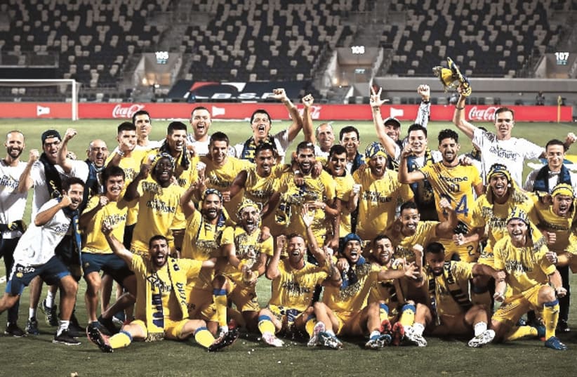MACCABI TEL AVIV celebrates on the pitch at Bloomfield Stadium on Saturday night after beating Hapoel Tel Aviv 3-0 to clinch a second straight Premier League championship. (photo credit: ARIEL SHALOM)