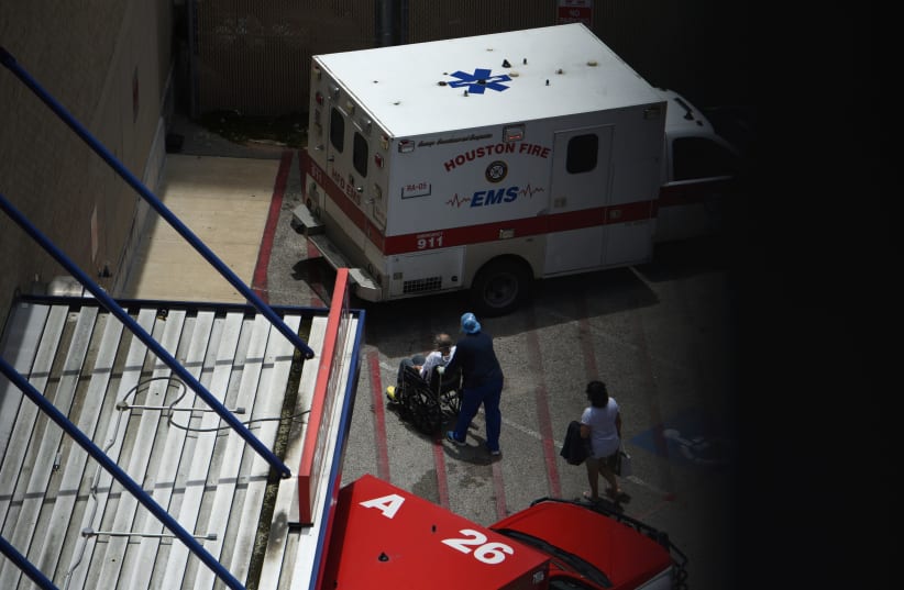 A nurse wheels away a man as the people who brought him to Houston Methodist Hospital watch amid a coronavirus disease (COVID-19) outbreak in Houston, Texas, U.S., June 28, 2020.  (photo credit: REUTERS/CALLAGHAN O’HARE)