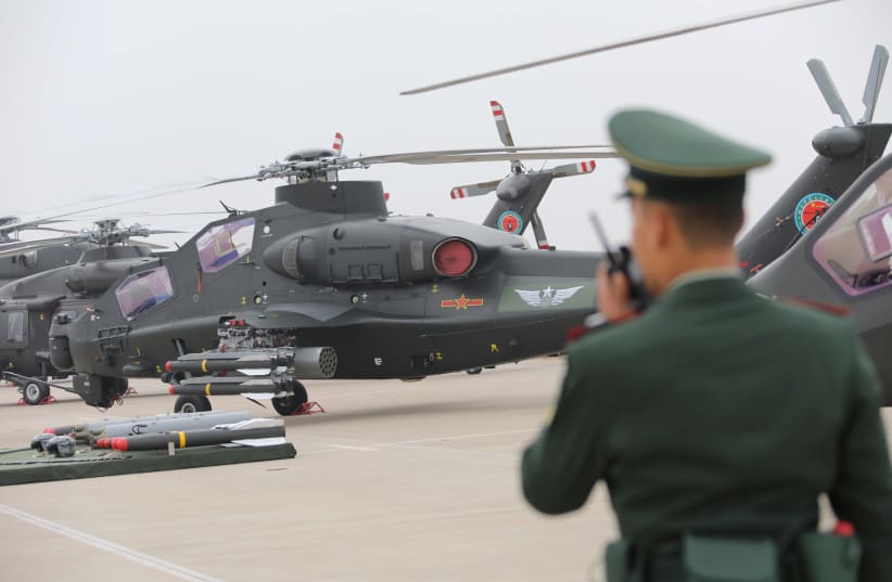 Military personnel speaks on his walkie-talkie before a military helicopter from Chinese People's Liberation Army (PLA) Air Force during the China Helicopter Exposition in Tianjin (photo credit: REUTERS)