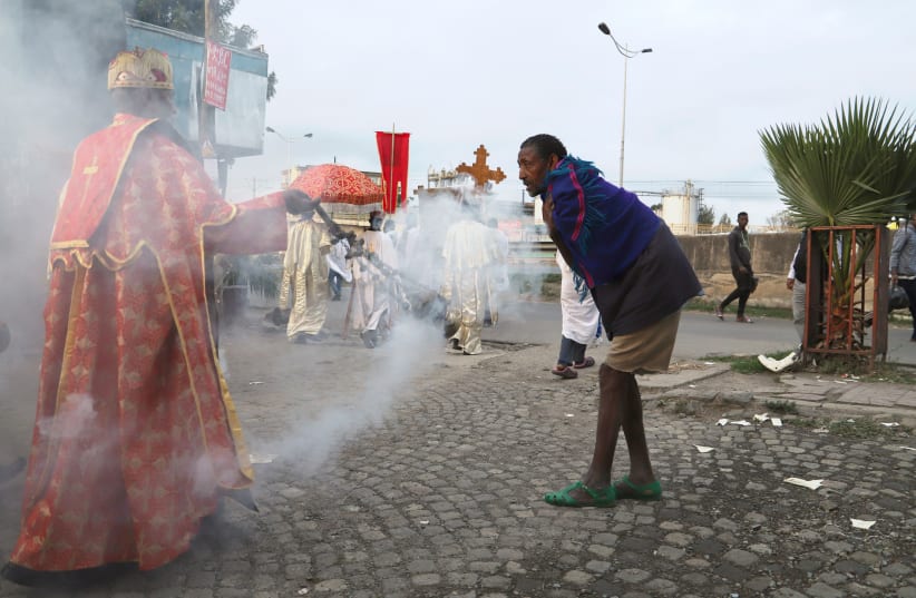An Ethiopian Orthodox Priest blesses the faithful with an incense which according to their belief will keep the coronavirus disease away, in Addis Ababa, Ethiopia March 26, 2020. (photo credit: REUTERS/TIKSA NEGERI)