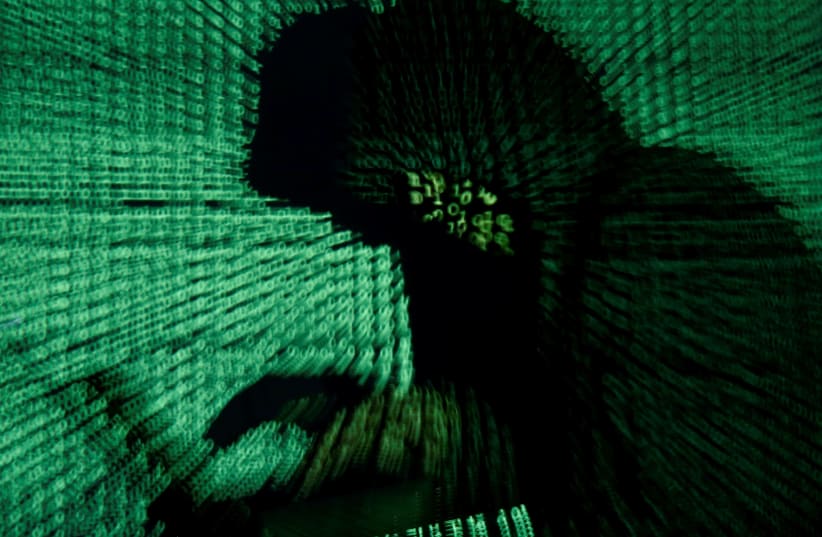 [Illustrative] A man holds a laptop computer as cyber code is projected on him. (photo credit: KACPER PEMPEL/REUTERS)