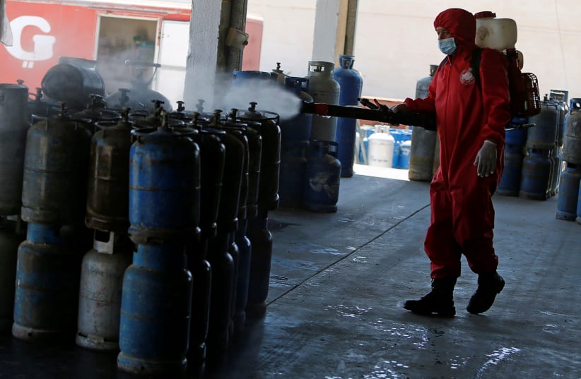 A Palestinian worker sanitizes gas cylinders in a filing station amid the coronavirus disease (COVID-19) outbreak, in Tubas in the West Bank July 1, 2020 (photo credit: REUTERS/RANEEN SAWAFTA)