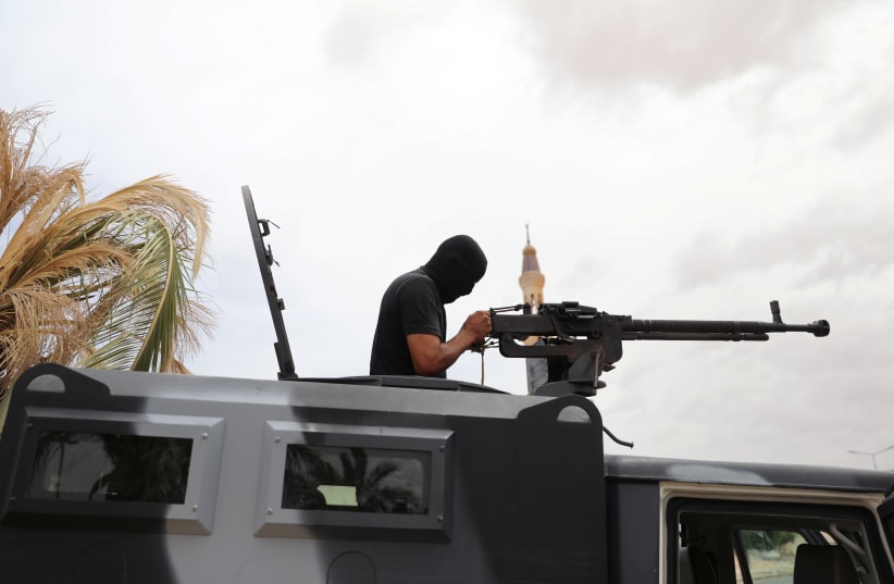A member of security forces loyal to Libya's internationally recognised government checks his weapon during a security deployment in Tarhouna city, Libya June 11, 2020.  (photo credit: ISMAIL ZITOUNY/ REUTERS)