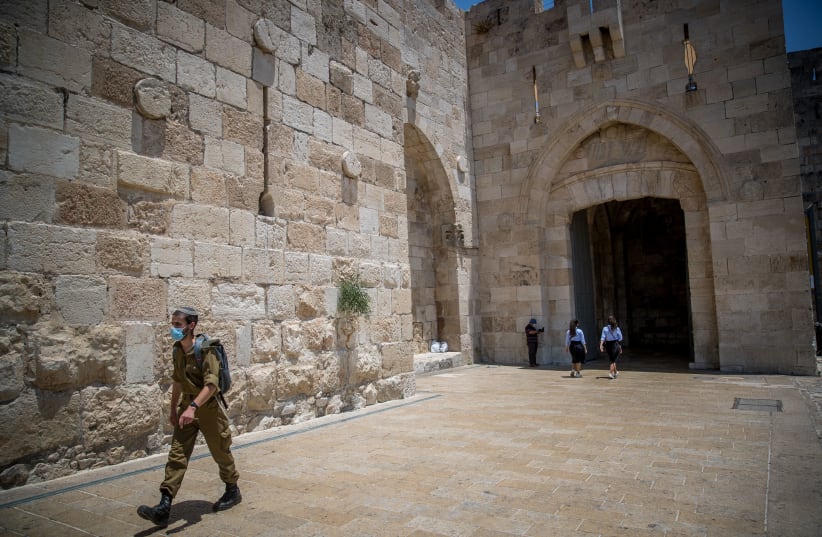 An Israeli soldier wearing a face mask walking in Jaffa Gate, outside Jerusalem Old City on July 5, 2020. (photo credit: YONATAN SINDEL/FLASH90)