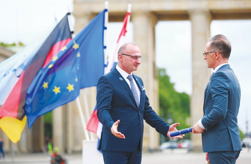GERMAN FOREIGN Minister Heiko Maas (right) takes over the rotating presidency of the Council of the European Union from Croatian Foreign Minister Gordan Grlic-Radman during a symbolic handover in front of the Brandenburg Gate in Berlin last week.  (photo credit: HANNIBAL HANSCHKE/REUTERS)
