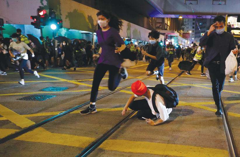 DEMONSTRATORS RUN from riot police shooting pepper-spray pellets during a protest in Hong Kong on June 9. (photo credit: TYRONE SIU/ REUTERS)