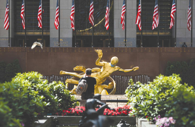 THE PROMETHEUS statue at Rockefeller Center in Manhattan is seen adorned with a face mask, earlier this week. (photo credit: JEENAH MOON/REUTERS)