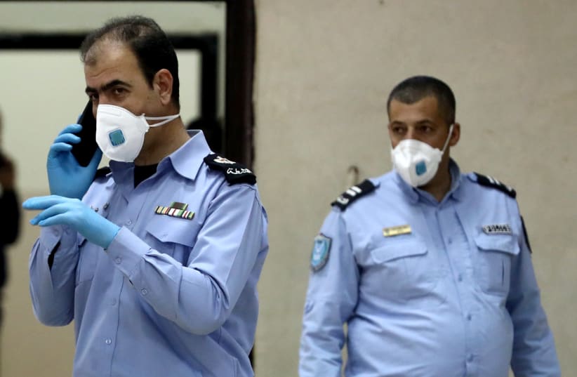 Palestinian police officers, wearing masks as a preventive measure against coronavirus (photo credit: REUTERS/AMMAR AWAD)