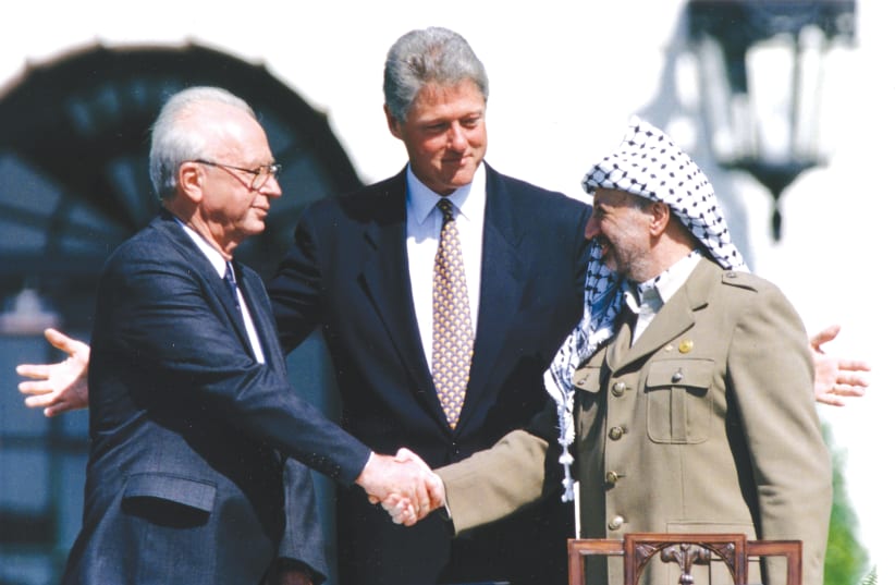 PLO CHAIRMAN Yasser Arafat shake hands with prime minister Yitzhak Rabin, as US president Bill Clinton stands between them, after the signing of the Israeli-PLO peace accord, at the White House, September 13, 1993. (photo credit: GARY HERSHORN/REUTERS)
