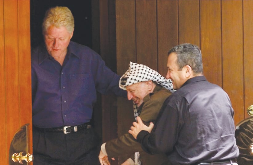 FORMER PRIME MINISTER Ehud Barak jokingly pushes Yasser Arafat into a building on the grounds of Camp David as then-US president Bill Clinton watches on, in 2000.  (photo credit: WIN MCNAMEE/REUTERS)