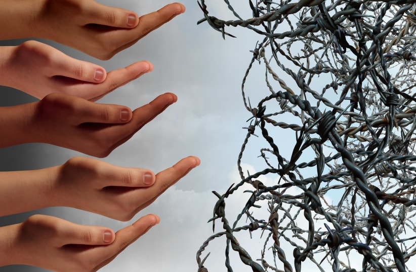 Hands reaching towards barbed wire (Illustrative) (photo credit: INGIMAGE)
