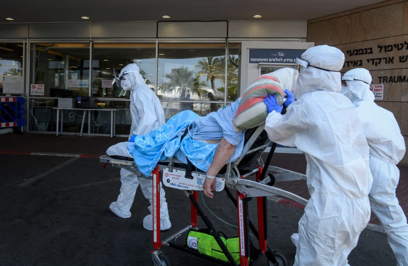 Magen David Adom workers wearing protective clothing evacuate a patient with suspicion to coronavirus outside the coronavirus unit at the Sheba Medical Center in Ramat Gan on July 8, 2020. (photo credit: FLASH90)