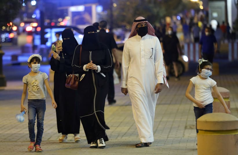 A Saudi family wearing protective face masks walk on Tahlia Street as nightlife kicks off, after the government loosened lockdown restrictions following the outbreak of the coronavirus disease (COVID-19), in Riyadh, Saudi Arabia June 21, 2020 (photo credit: AHMED YOSRI/ REUTERS)
