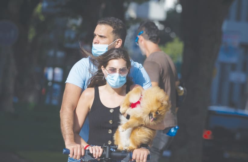 A MASKED couple scoots along Tel Aviv’s Rothschild Boulevard on July 8 (photo credit: MIRIAM ALSTER/FLASH90)
