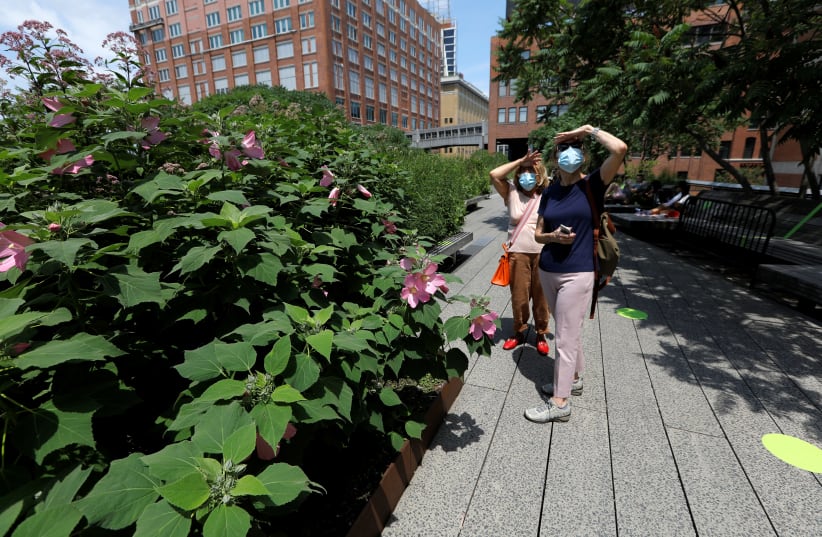 Women wearing protective face masks pause to take in a view as they walk on the elevated High Line Park in Manhattan on the first day of the park's re-opening following the outbreak of the coronavirus disease (COVID-19) in New York City, New York, U.S., July 16, 2020 (photo credit: REUTERS/MIKE SEGAR)