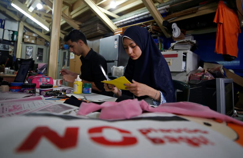 Palestinians decorate cloth bags as part of a project aiming at replacing plastic bags in shops, in Gaza City July 12, 2020 (photo credit: REUTERS/MOHAMMED SALEM)
