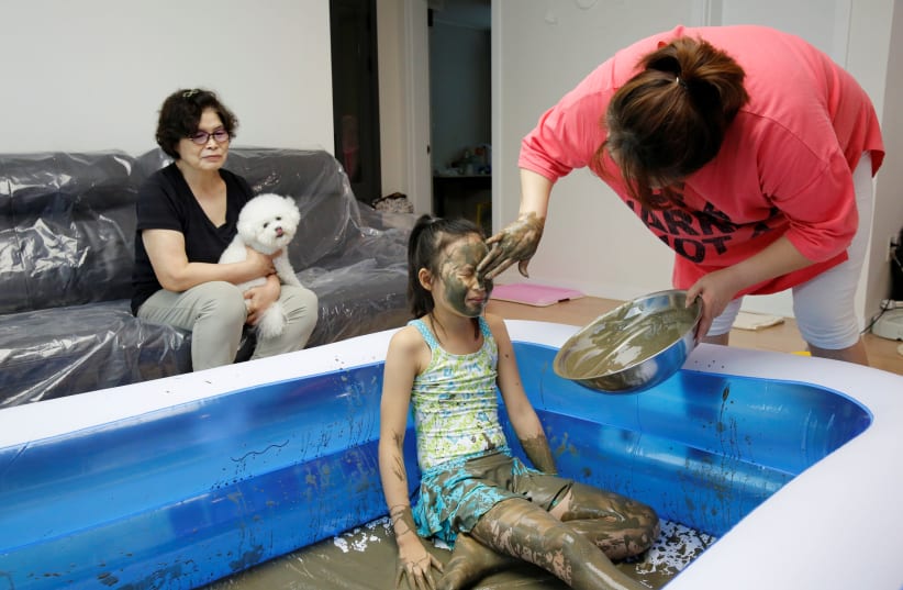 A girl with colored mud on her face is seen during the Online Boryeong Mud Festival at her home during a live streaming event, in Gwangju, Gyeonggi-do, South Korea, July 18, 2020.  (photo credit: REUTERS/HEO RAN)