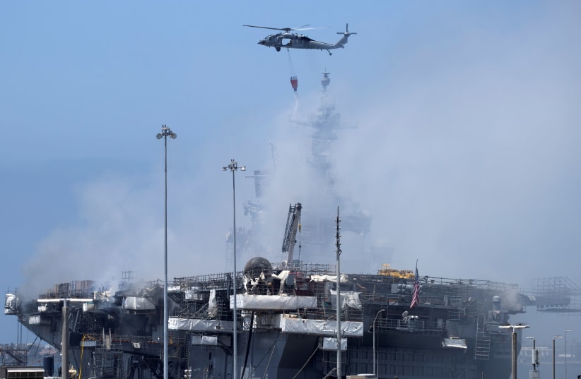 A US Navy helicopter continues fighting a fire on the amphibious assault ship USS Bonhomme Richard at Naval Base San Diego, in San Diego, California, US July 13, 2020 (photo credit: REUTERS/MIKE BLAKE)