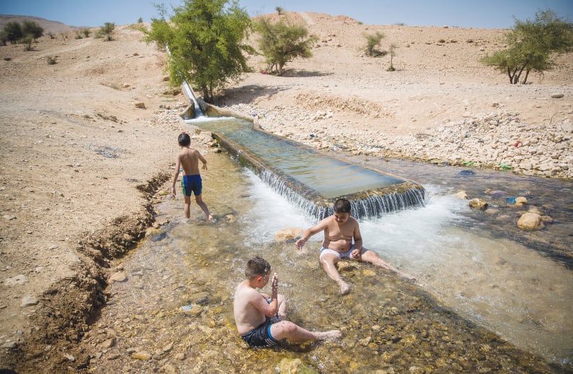 PALESTINIANS ENJOY a water spot near Jericho, earlier this month. ‘Given that ecosystems transcend political borders, irresponsible exploitation of natural resources or pollution on one side of the border can damage natural trans boundary habitats and the natural resources of those living on its oth (photo credit: YONATAN SINDEL/FLASH90)
