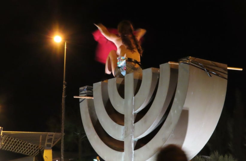A naked woman on top of menorah statue during Jerusalem protests, July 21, 2020 (photo credit: IM TIRTZU)