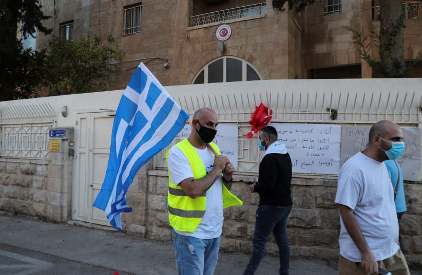 A Palestinian Christian man carries a Greek flag outside Turkey's consulate, during a protest against Ankara's decision to convert Istanbul's ancient Hagia Sophia from a museum back into a mosque, in Jerusalem July 13, 2020. (photo credit: REUTERS/AMMAR AWAD)