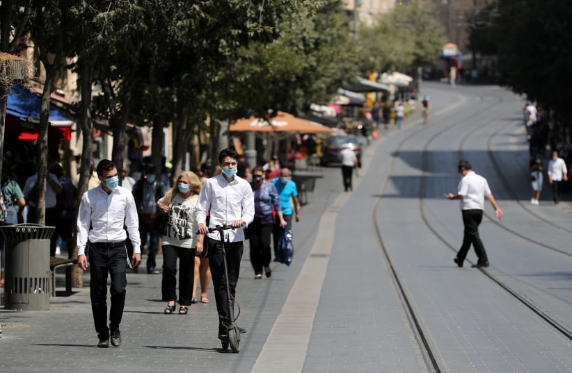 People wear protective masks as they walk around central Jerusalem amid the spread of the coronavirus disease (COVID-19), July 7, 2020 (photo credit: REUTERS/AMMAR AWAD)