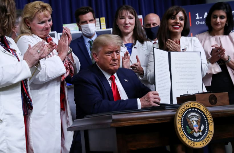 U.S. President Donald Trump is applauded as he displays an executive order on lowering drug prices during a signing ceremony in the Eisenhower Executive Office Building at the White House in Washington, U.S., July 24, 2020 (photo credit: REUTERS/LEAH MILLIS)