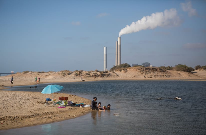 A power station seen in the background of where Israelis enjoy swimming in a lake by the Zikim beach, Southern Israel, near the border with Gaza on July 06, 2015.  (photo credit: MIRIAM ALSTER/FLASH90)