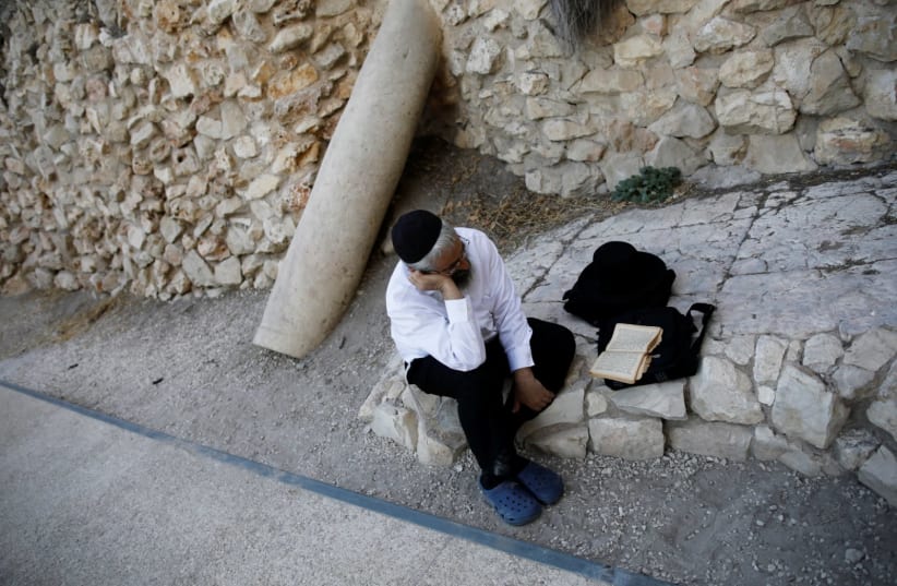 A Jewish worshipper prays next to the Western Wall on Tisha B'Av, a day of fasting and lament, in Jerusalem's Old City (photo credit: REUTERS/AMIR COHEN)