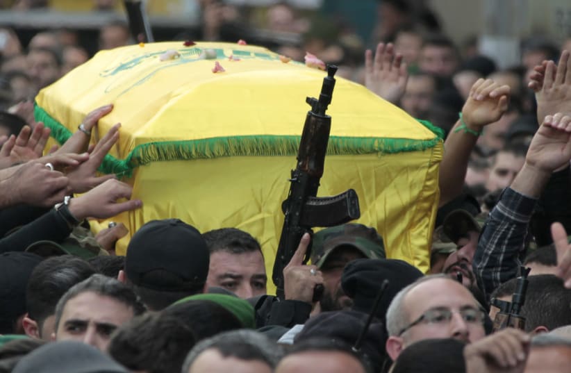 Lebanon's Hezbollah members raise their fists and rifles while carrying the coffin of Jihad Moughniyah during his funeral in Beirut's suburbs, 2015 (photo credit: AZIZ TAHER/REUTERS)