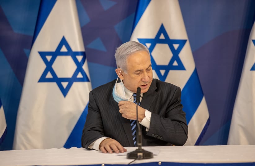 Prime Minister Benjamin Netanyahu removing his mask (photo credit: ELI DASSA)