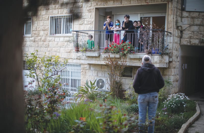A FAMILY practicing social distancing talks to a friend from their balcony, in April in Jerusalem (photo credit: HADAS PARUSH/FLASH90)