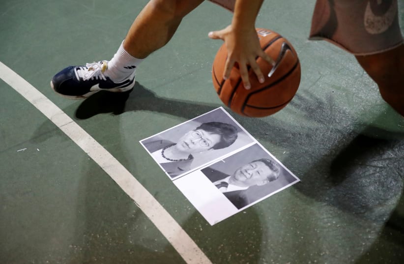 A protester dribbles a basketball over pictures of China's President Xi Jinping and Hong Kong Chief Executive Carrie Lam during gathering in support of NBA's Houston Rockets' team general manager Daryl Morey, who sent a tweet backing the pro-democracy movement, in Hong Kong, China, October 15, 2019 (photo credit: UMIT BEKTAS / REUTERS)