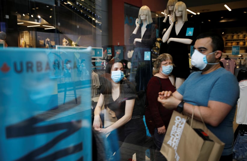 Shoppers wear face masks and walk around a fashion shopping center in Ashdod, as restrictions over the coronavirus disease (COVID-19) ease around Israel, May 5, 2020 (photo credit: REUTERS/AMIR COHEN)