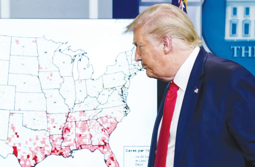 US PRESIDENT Donald Trump walks past a map of reported coronavirus cases following a news briefing at the White House on July 23. (photo credit: KEVIN LAMARQUE/REUTERS)
